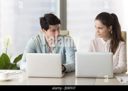 Rivalry between male and female colleagues, angry coworkers look Stock Photo