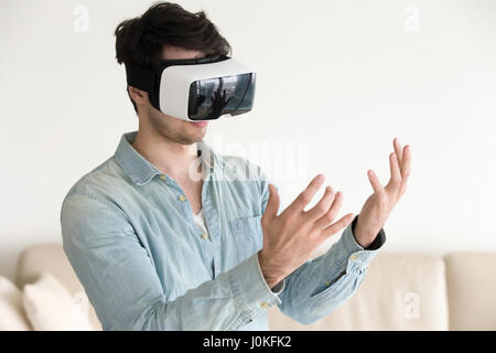 Man in virtual reality headset glasses looking at his hands Stock Photo