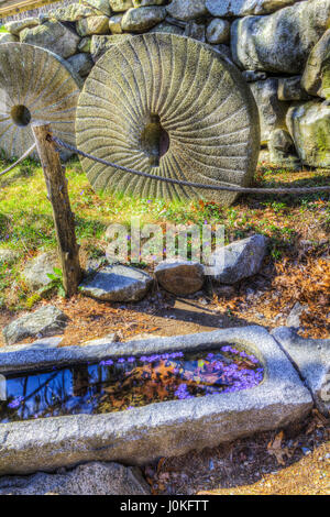 Granite millstones and a granite water trough at the entrance to The Old Grist Mill in Sudbury, Massachusetts. Stock Photo