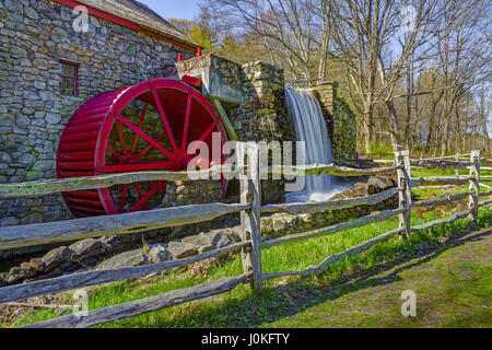 Red metal water wheel and waterfall headrace of the Old Grist Mill in Sudbury, Massachusetts. Stock Photo