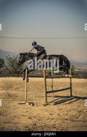 Equestrian sports Black horse approaching. Jockey riding a fast thoroughbred horse Stock Photo