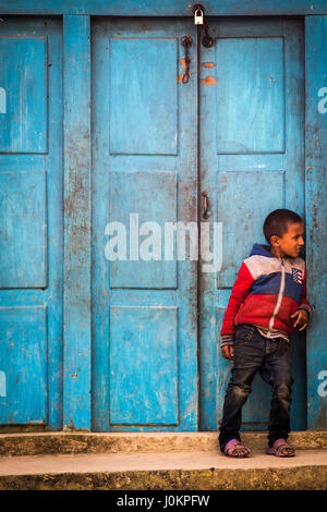 A young boy watches his friends play football in a small village in Nepal, just outside of Kathmandu Stock Photo