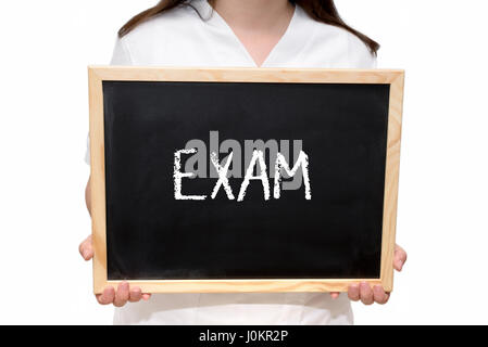Female nurse holding a slate board with the text Exam written with chalk, isolated on white background. Stock Photo