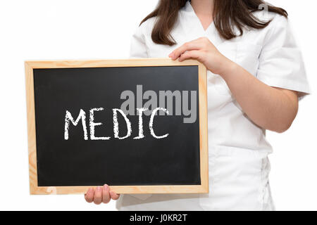Female nurse holding a slate board with the text Medic written with chalk, isolated on white background. Stock Photo