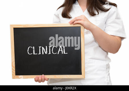 Female nurse holding a slate board with the text Clinical written with chalk, isolated on white background. Stock Photo