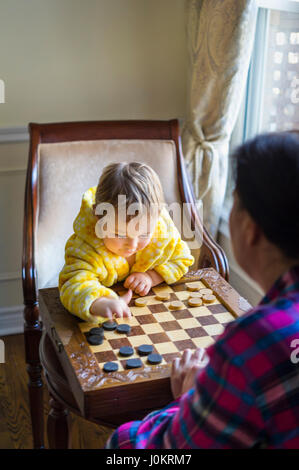 2 years-old boy playing with checkers Stock Photo