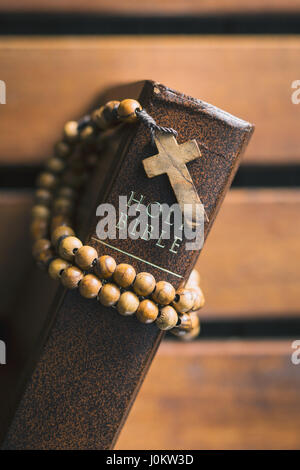 Rosary beads and holy bible on wooden table. Top view. Stock Photo