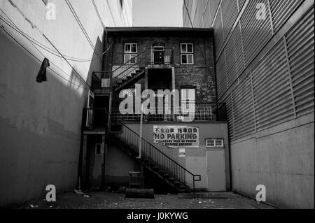 Old brick building squeezed between to concerete buildings. Stock Photo