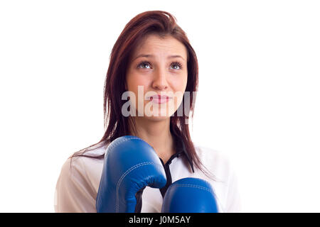 Cute young woman in white shirt with dark hair and blue boxing gloves on white background in studio Stock Photo