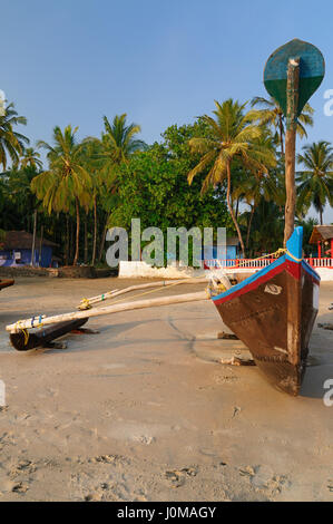 Sand tropical beach with coconut trees and traditional boat - Palolem beach, Goa, India Stock Photo