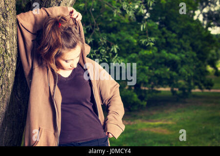 Young woman in sports clothes resting in a park after a morning workout. Leisure time activity concept. Toned image Stock Photo