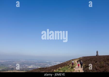 Family walking towards Darwen Jubilee Tower in bright sunshine with Blackburn town in the distance Stock Photo