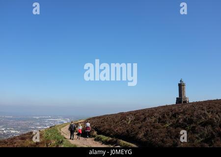 Family walking towards Darwen Jubilee Tower in bright sunshine with Blackburn town in the distance Stock Photo