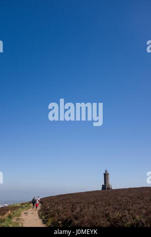 Family walking towards Darwen Jubilee Tower in bright sunshine with Blackburn town in the distance Stock Photo