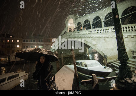 A woman poses in front of Rialto bridge during an heavy snow fall in Venice. Stock Photo