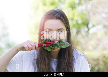 Young woman eating leaf vegetable Stock Photo