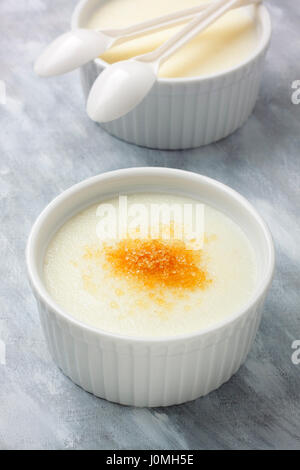 Ramekins filled by wheat semolina (farina) with milk and brown cane sugar. Focus on first ramekin. Stock Photo