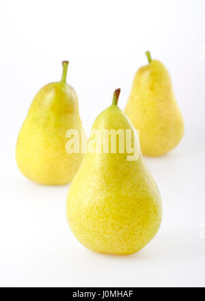 Three yellowgreen pears on bright background. Focus on front pear. Stock Photo