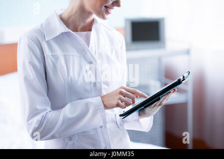 Partial view of smiling female doctor using digital tablet in hospital Stock Photo