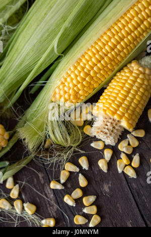 Fresh corn on cobs and corn grain on rustic wooden table Stock Photo