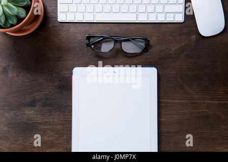 Top view of digital tablet, eyeglasses, computer mouse and keyboard on office desk Stock Photo