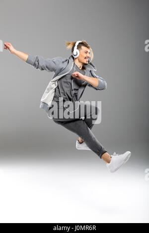 Handsome young athletic man in headphones dancing on white Stock Photo