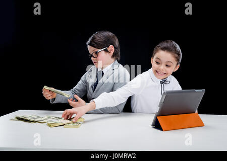 kids playing business people with money and tablet on black Stock Photo