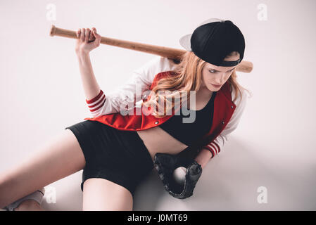 Young sporty woman lying with baseball bat, glove and ball Stock Photo