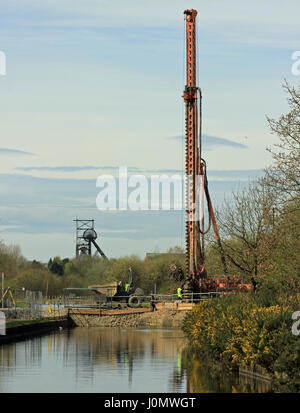 Bridge replacement works over the Bridgewater canal with large machinery at work while in the distance is the last pit head gear in Lancashire. Stock Photo