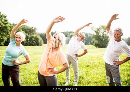 Four people in field exercising. Stock Photo