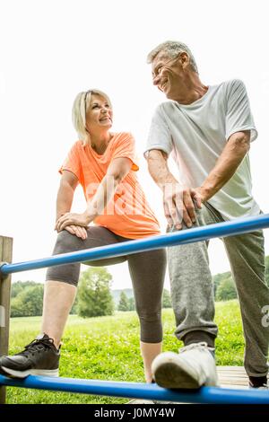 Couple smiling towards each other with legs on railings. Stock Photo