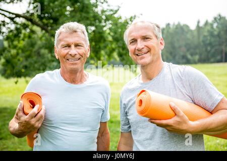 Two men with yoga mats, smiling. Stock Photo