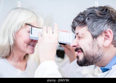 Optometrist performing eye test of senior woman with vision screener in optometrist's shop. Stock Photo