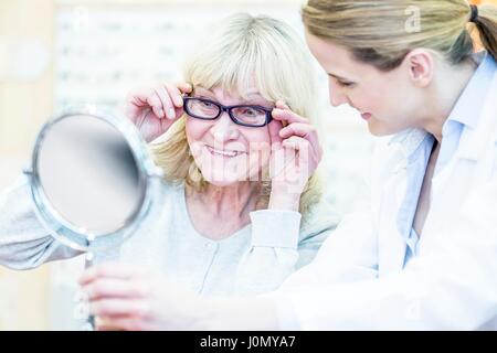 Optometrist counselling senior woman in optometrist's shop. Stock Photo