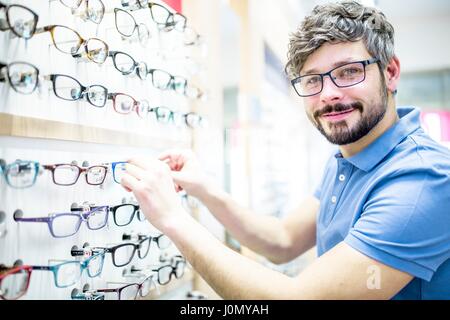 Man near glasses rack in optometrist's shop. Stock Photo