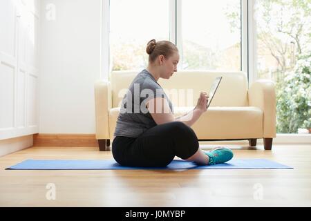 Woman sitting on floor using digital tablet. Stock Photo