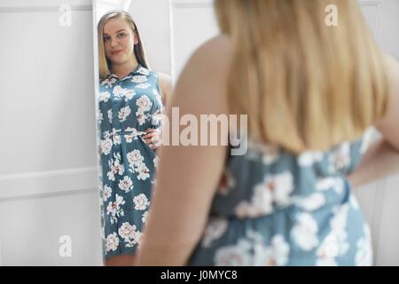 Young woman looking at reflection in mirror, smiling. Stock Photo