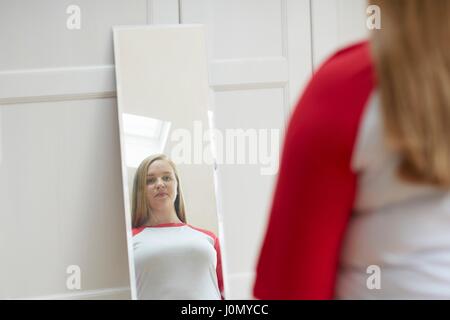 Young woman looking at reflection in mirror. Stock Photo