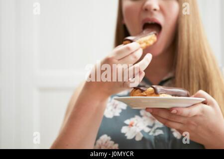 Young woman eating chocolate eclair. Stock Photo