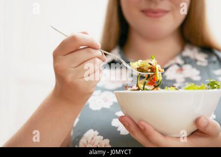Young woman eating bowl of salad. Stock Photo
