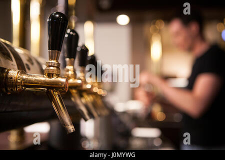 Lot of vintage Golden beer taps in the bar with the bartender in the background Stock Photo