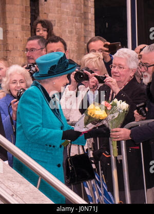 Queen Elizabeth II is presented with flowers by a young boy on stage at