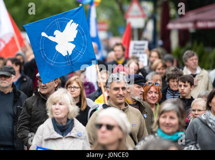 Munich, Germany. 15th Apr, 2017. A member of the peace movement carries a flag with a peace dove during the Easter March in Munich, Germany, 15 April 2017. By holding Easter Marches throughout the german federal state of Bavaria, the protesters aim to raise awareness about regions across the world afflicted by war and crisis and to warn about the increasingly tense global political situation. Photo: Matthias Balk/dpa/Alamy Live News Stock Photo
