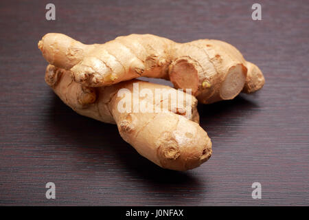 Ginger root (rhizome) lying on dark board Stock Photo