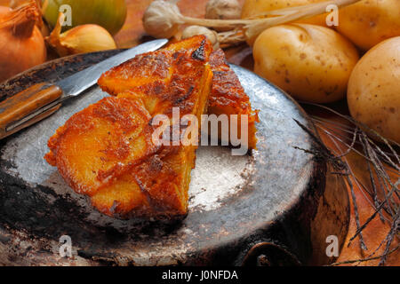 Still life with two pieces of Tortilla Espanola (Spanish omelet with potatoes and onions) lying over inverted frying-pan Stock Photo