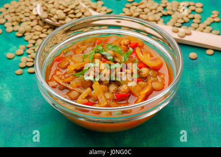 Glass bowl with lentils soup on green painted textile background Stock Photo
