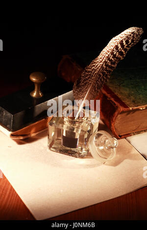 Literature concept. Stylish vintage inkwell near old book on dark background Stock Photo