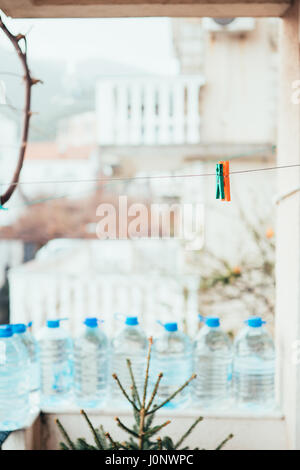 Multicolored clothespins on a rope for drying clothes, against a background of a stone wall. Stock Photo