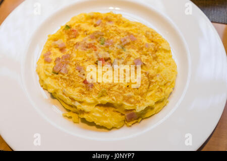 Delicious Egg Omelette with Vegetables and ham bacon on white Plate on wooden table Stock Photo