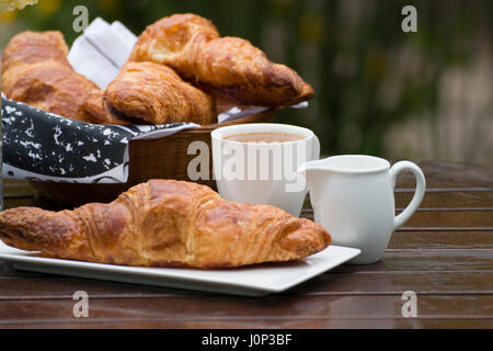 Croissants, cup of coffee and milk, on a wooden table in natural light. Stock Photo